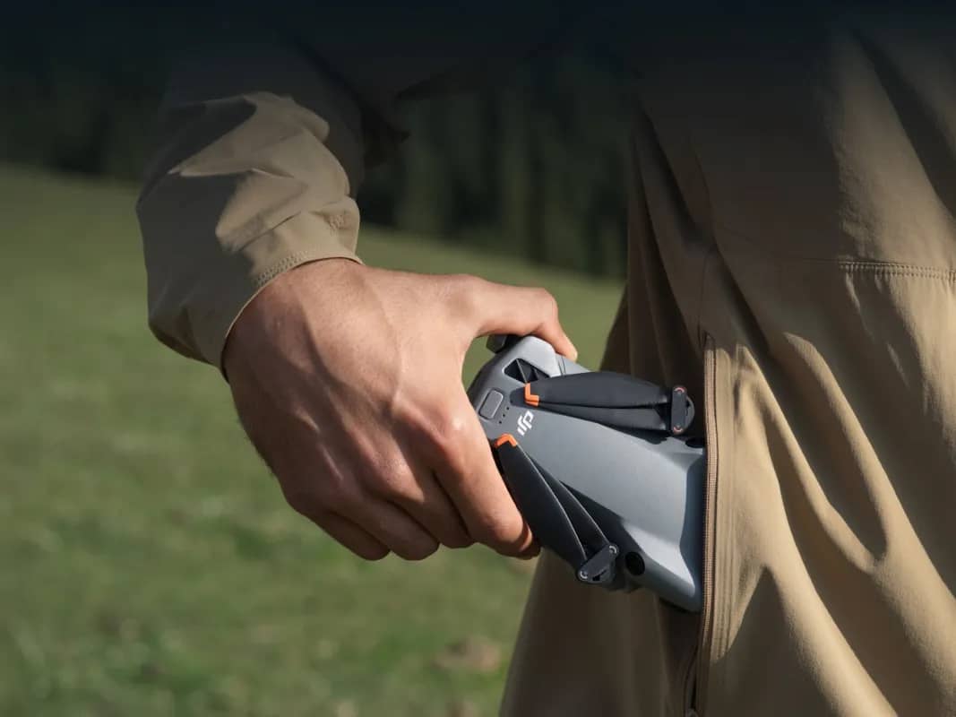 Le DJI Mini 5 Pro replié, tenu d’une main au bord d’une poche de pantalon