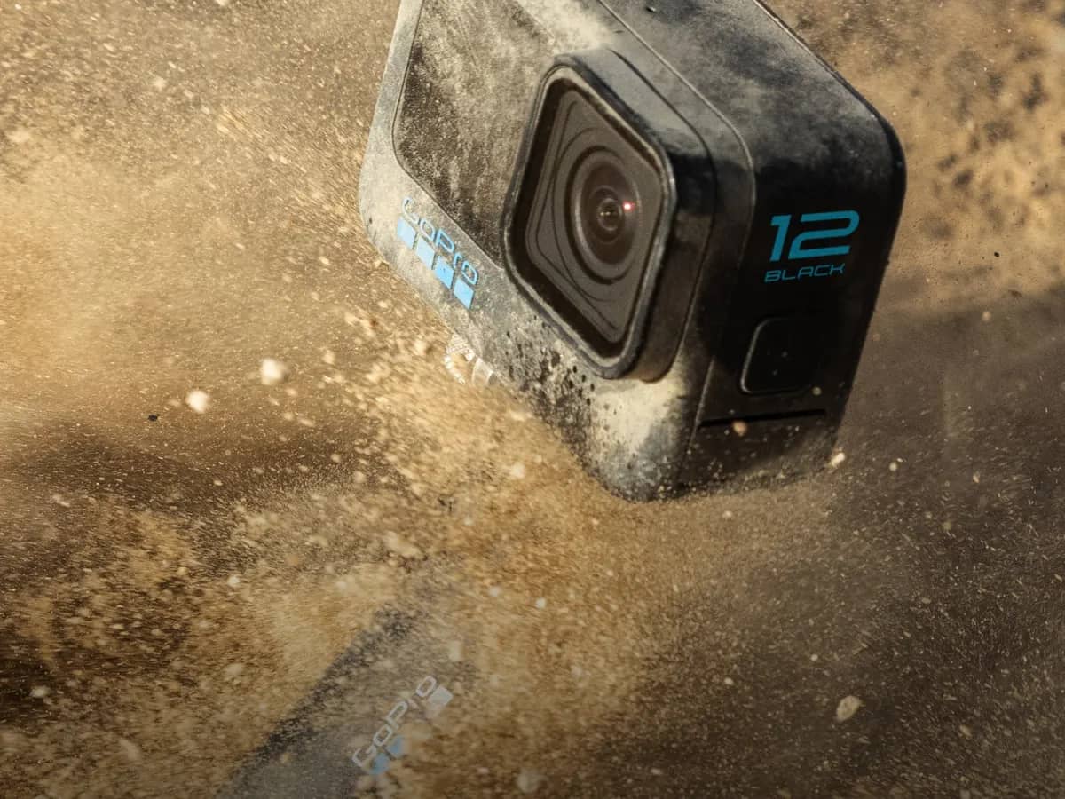 GoPro Hero 12 Black projetée dans un nuage de sable, boîtier couvert de poussière