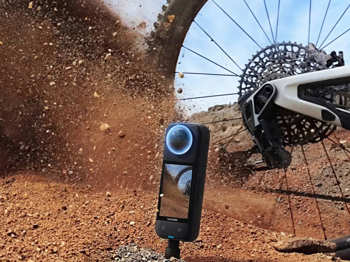 Insta360 X4 plantée au bord d’un sentier, dans la terre soulevée par la roue d’un VTT