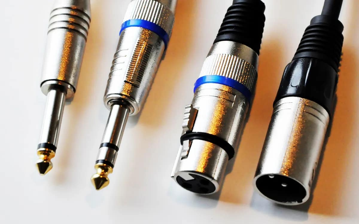 A mono jack plug, a stereo jack plug and two XLR plugs, male and female, in close-up