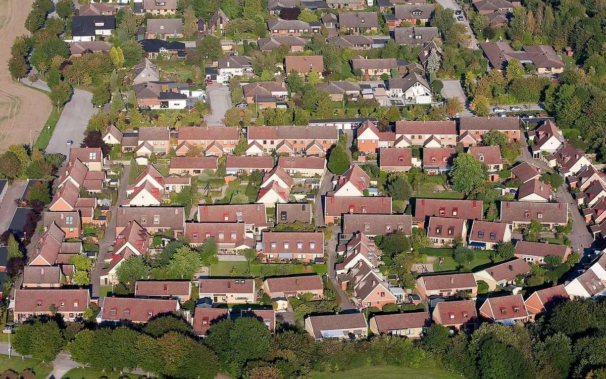 Woonwijk bijna loodrecht van boven: rijtjeshuizen, smalle tuinen en hagen die elke grens markeren