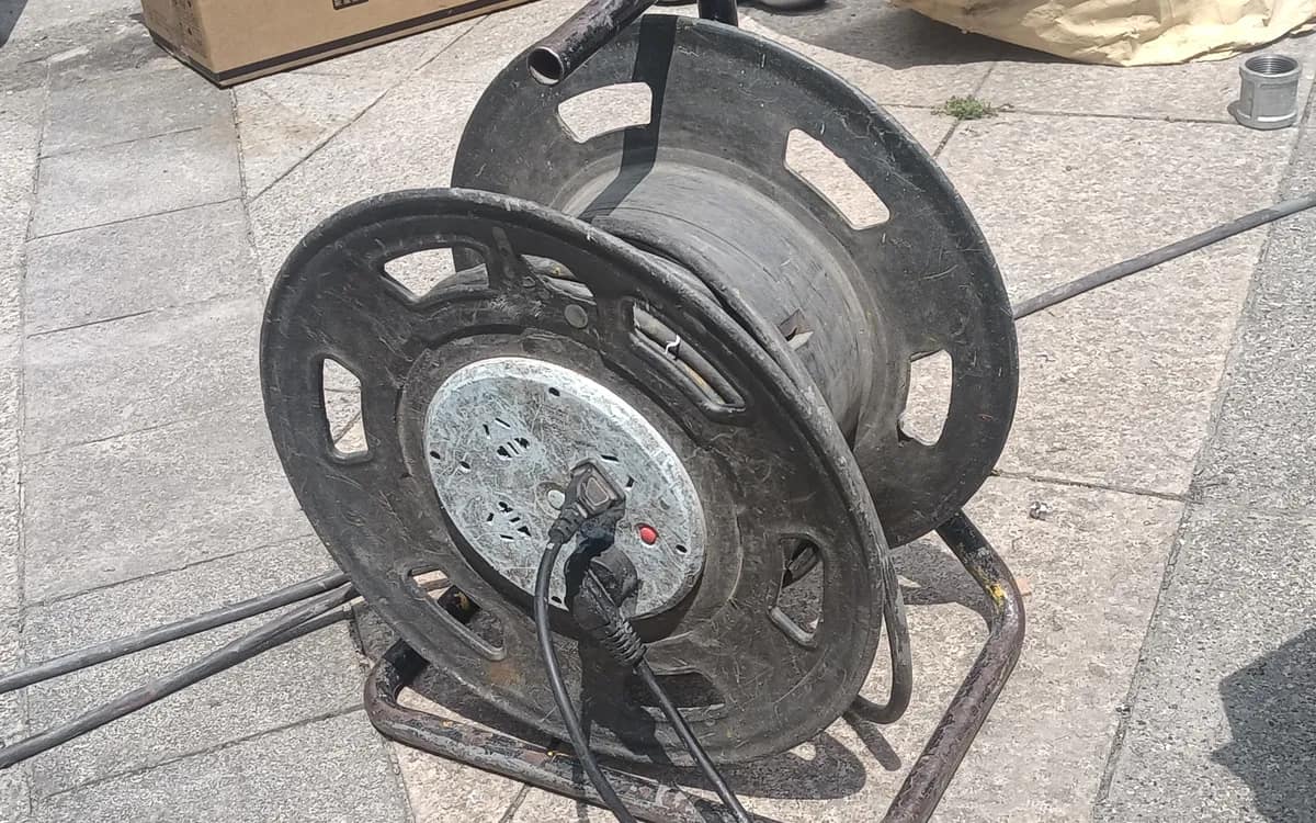 An extension cable reel on a paved floor, its cable unrolled