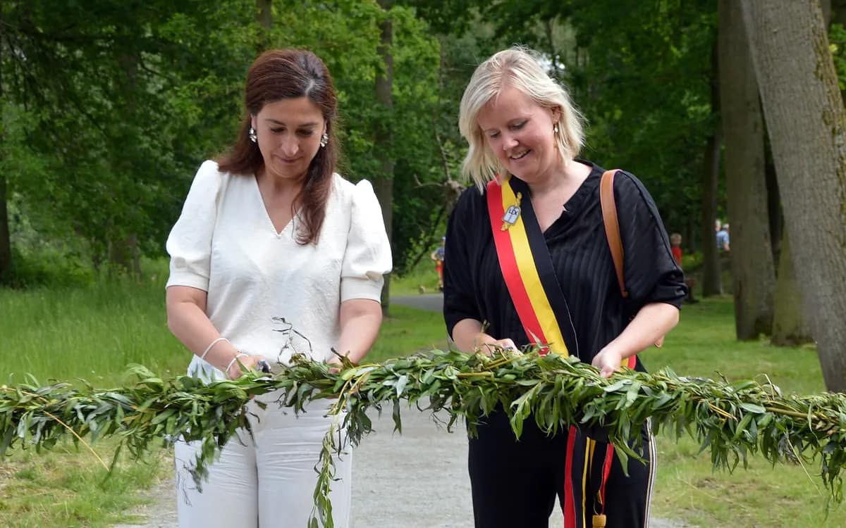 Deux femmes coupent une guirlande de branchages lors d’une inauguration en plein air