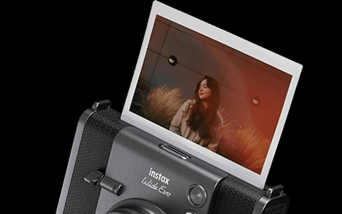 Appareil instax WIDE Evo posé à côté de cartouches de film instax WIDE et de tirages fraîchement sortis