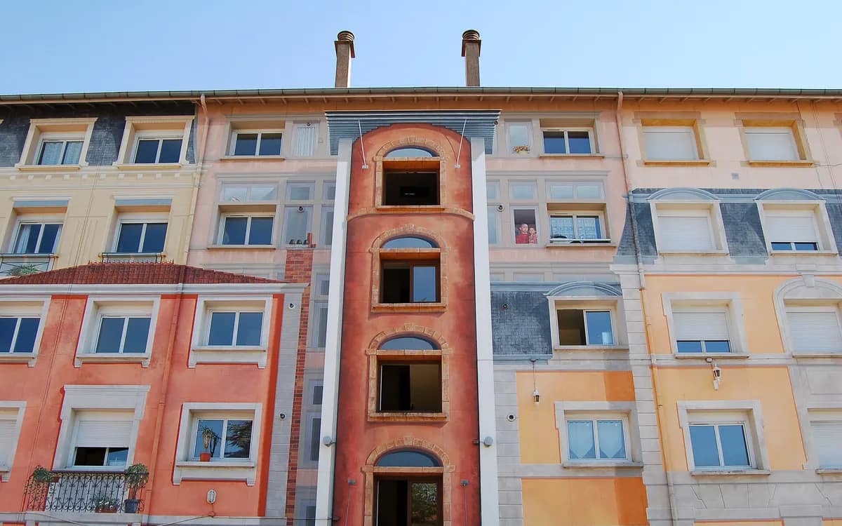 Fassade eines Lyoner Wohnhauses in Ocker- und Rottönen, mit ihren Fensterreihen und dem mittigen Treppenhaus