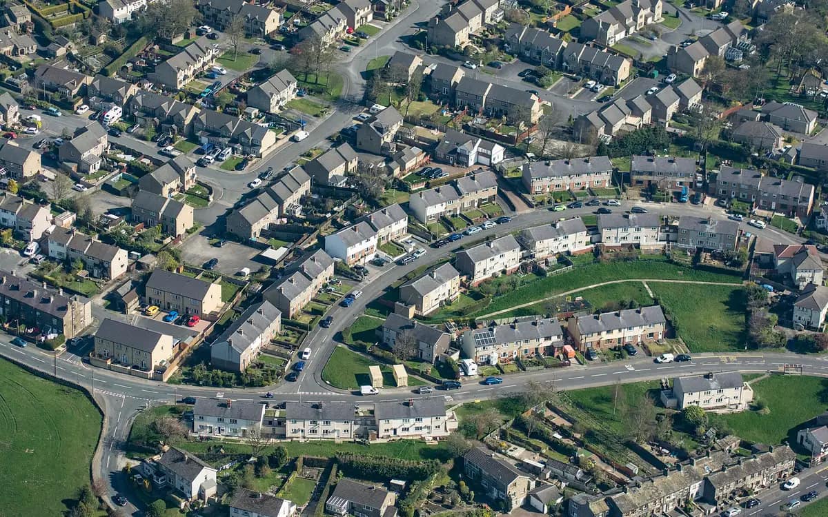 Quartier pavillonnaire vu du ciel en oblique, rues courbes, toits d’ardoise et jardins mitoyens