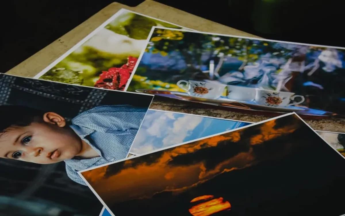 Tirages photo grand format éparpillés en désordre sur une table, portraits et paysages mêlés