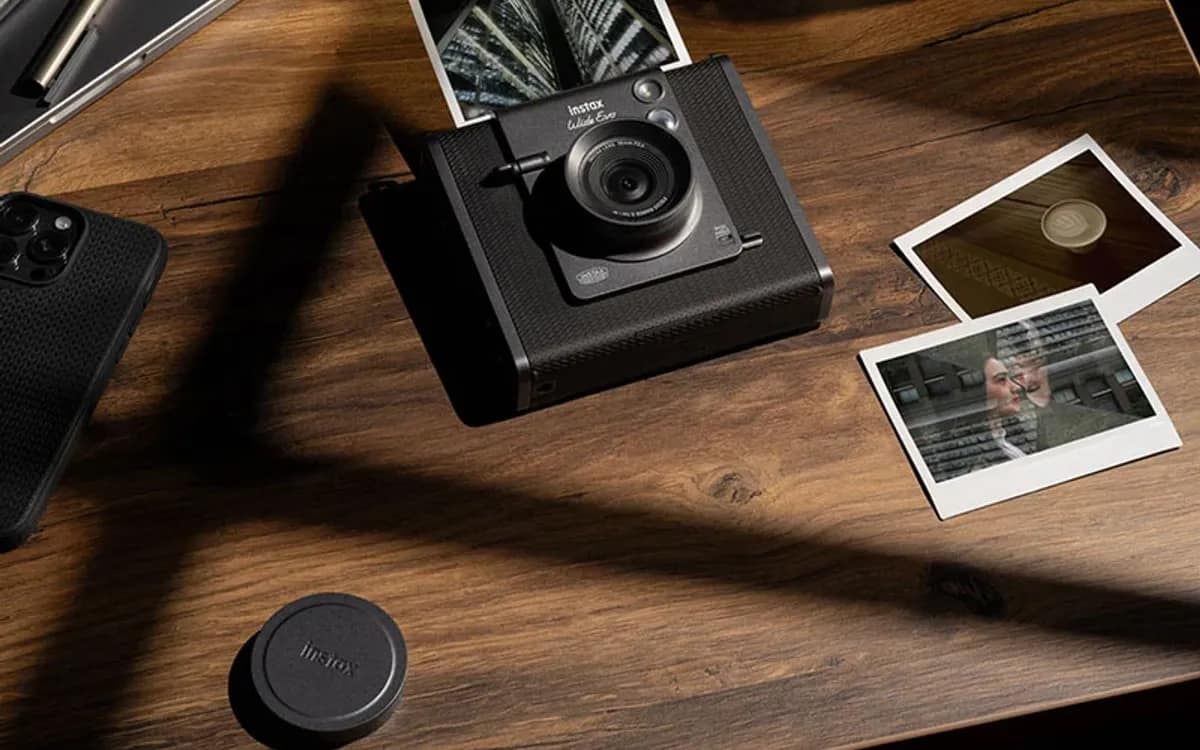 L’instax WIDE Evo posé sur une table en bois, entouré de tirages instantanés
