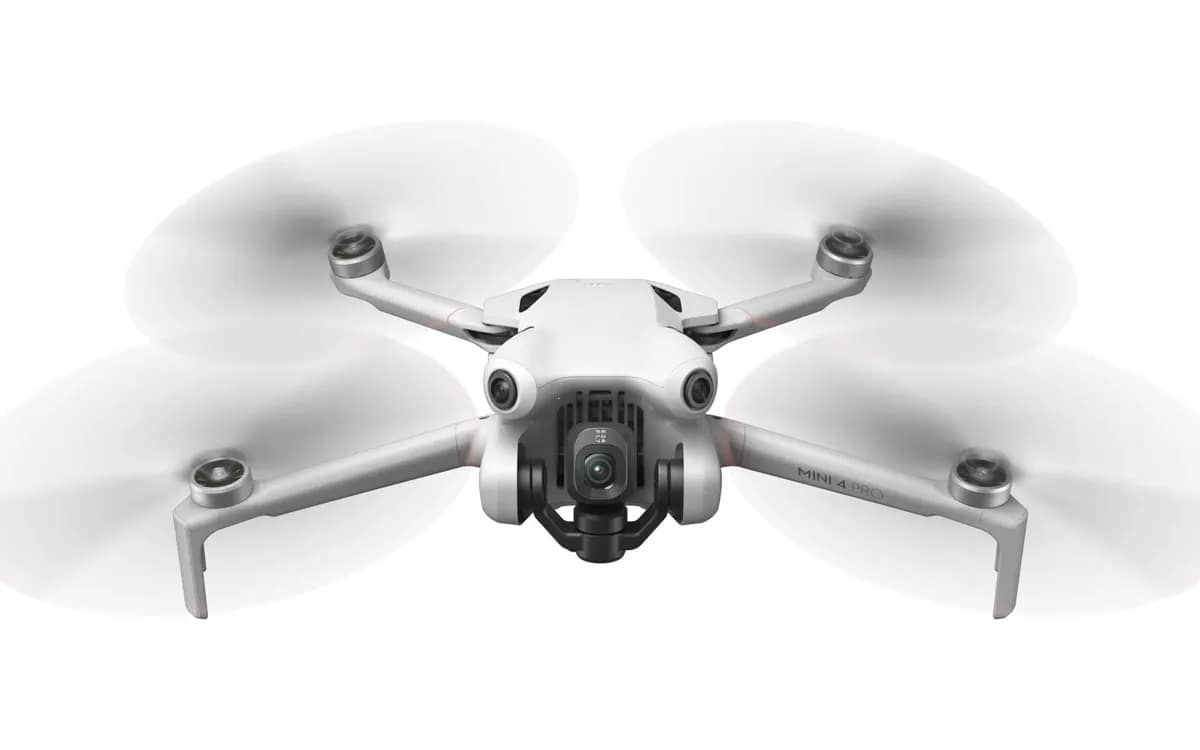 DJI Mini 4 Pro déplié en vol stationnaire, vu de face sur fond blanc