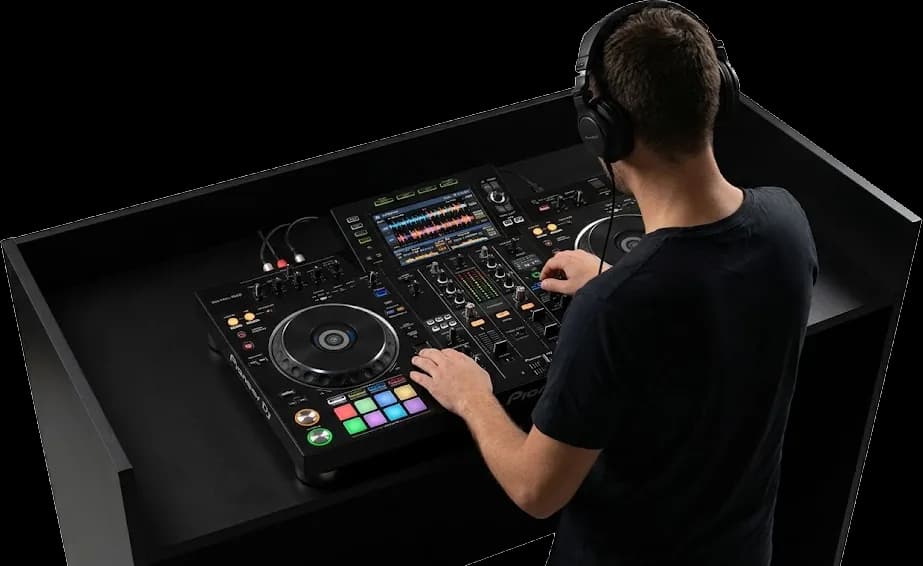 DJ di spalle, con le cuffie, davanti a un controller Pioneer su una consolle nera