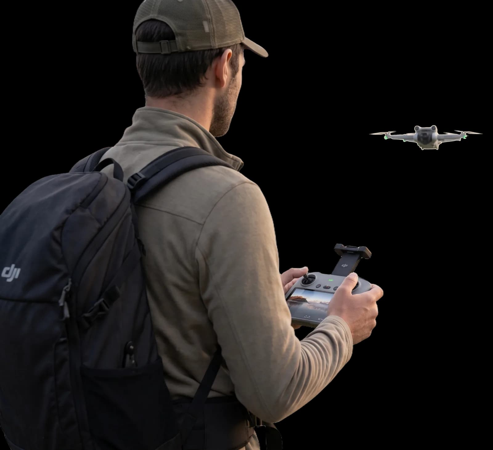 Pilota di drone di spalle, radiocomando in mano, drone in volo