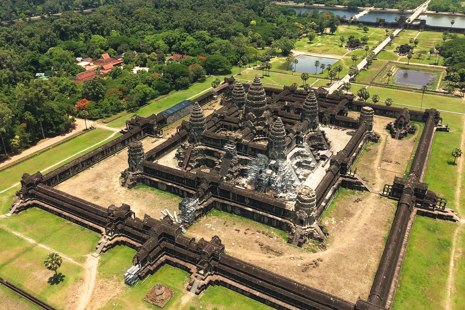 Aerial view of a vast ancient temple surrounded by moats and tropical forest
