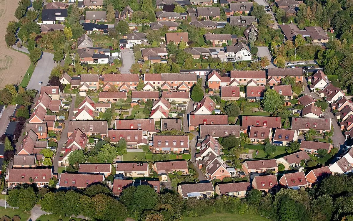 Woonwijk bijna loodrecht van boven: rijtjeshuizen, smalle tuinen en hagen die elke grens markeren