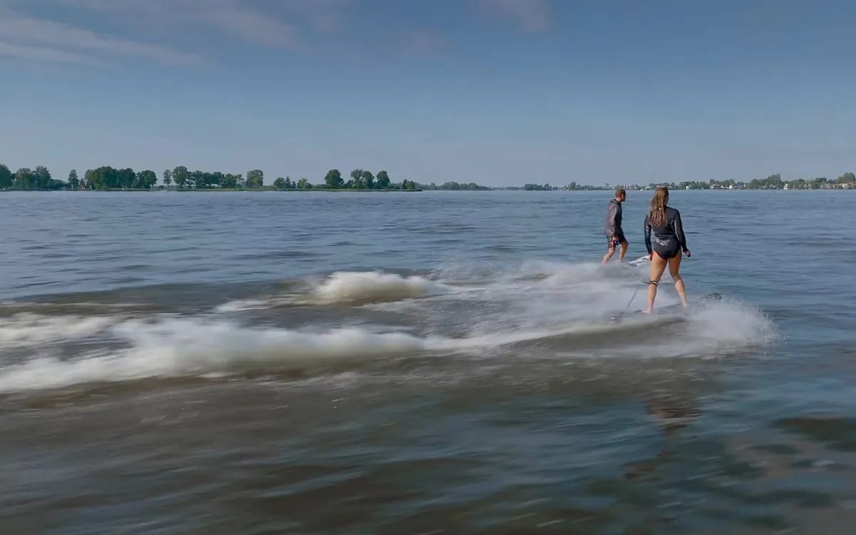 Vue aérienne de deux personnes en wakesurf sur un lac, filmées depuis un drone DJI