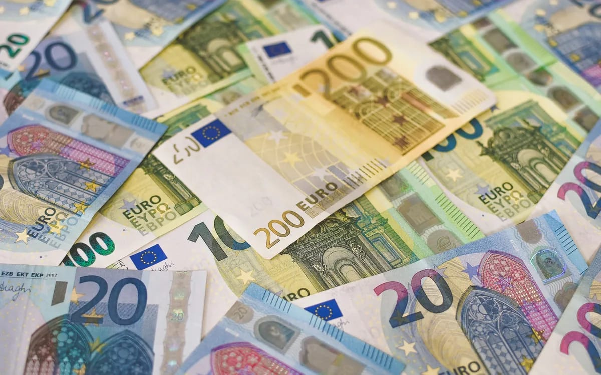 Gros plan sur des billets en euros étalés à plat et se chevauchant : un 200 € au centre, entouré de 100 €, 50 € et 20 €.