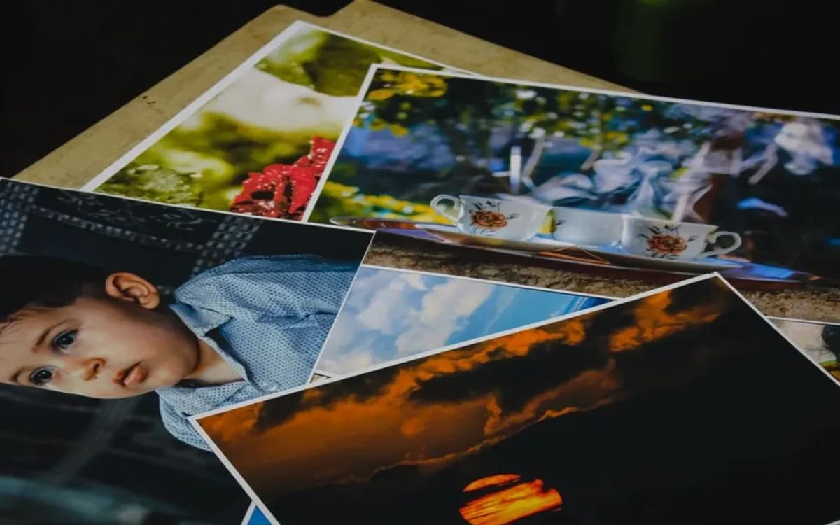Tirages photo grand format éparpillés en désordre sur une table, portraits et paysages mêlés
