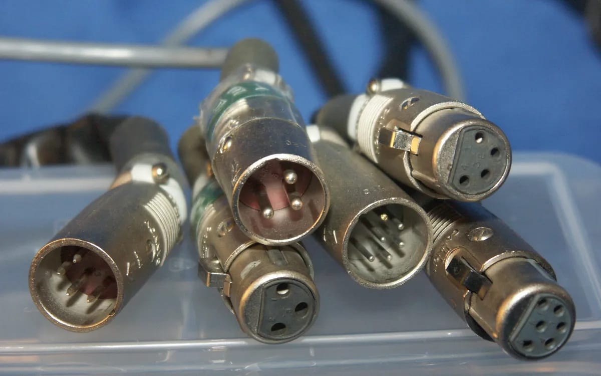 Close-up of several male and female XLR connectors gathered in a transparent bin