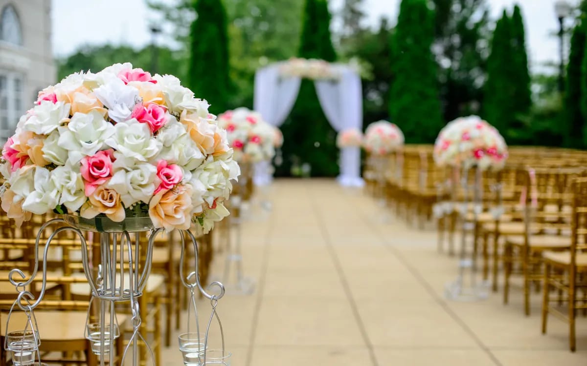 Une allée de cérémonie bordée de chaises dorées et de bouquets, avant les invités