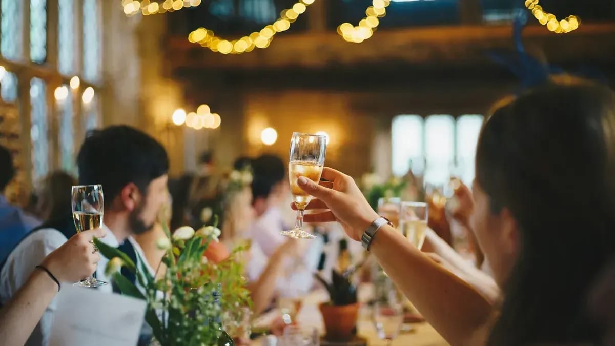 Banquet de mariage : les convives lèvent leurs verres sous des guirlandes
