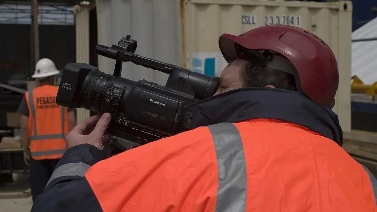 Un opérateur en gilet haute visibilité et casque filme sur un chantier