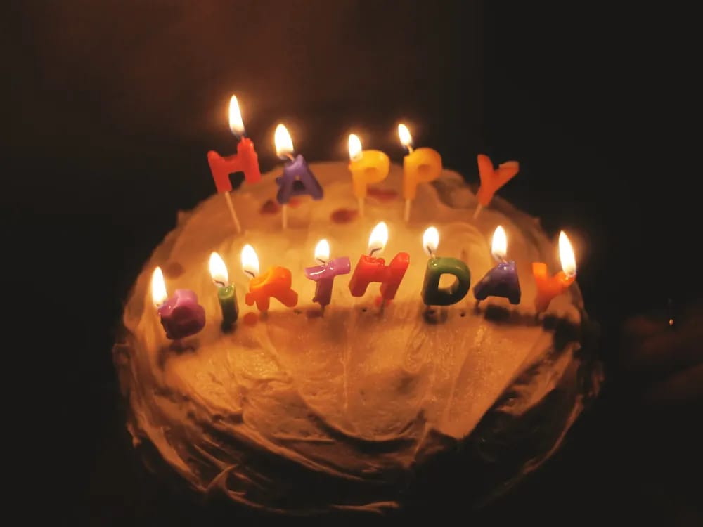 Birthday cake with lit candles in the dark