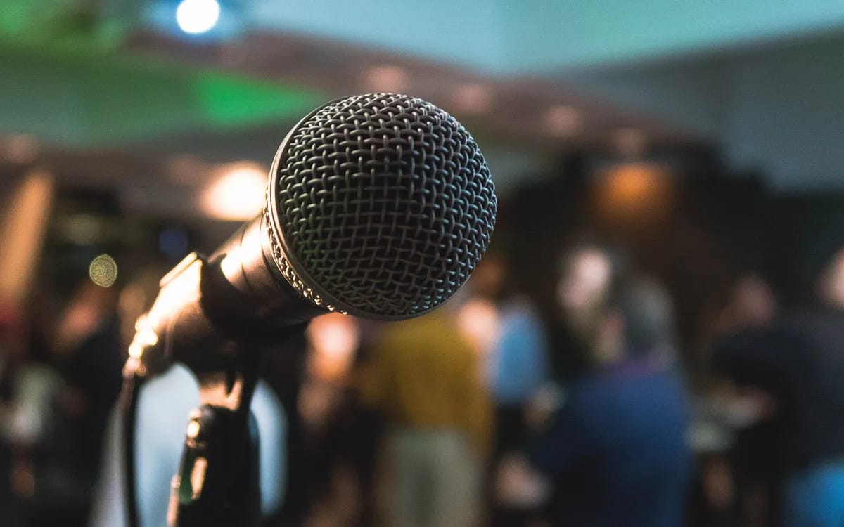 Micro à main en gros plan, salle floue et debout derrière