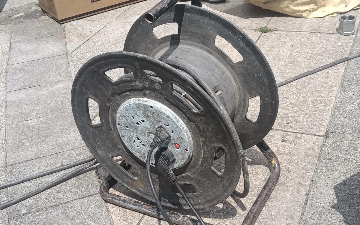 An extension cable reel on a paved floor, its cable unrolled