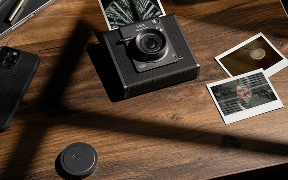 L’instax WIDE Evo posé sur une table en bois, entouré de tirages instantanés