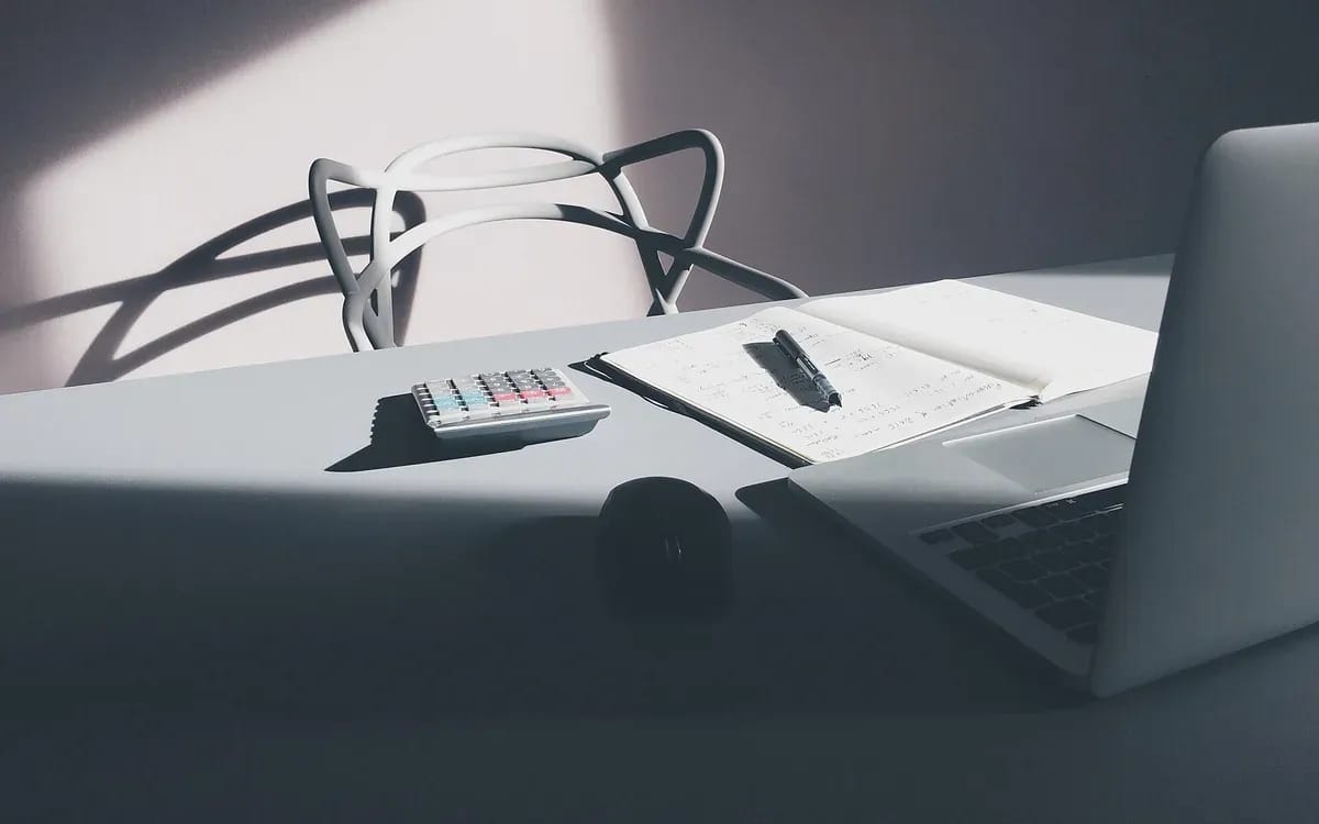 Bureau en bois avec un ordinateur portable, une paire de lunettes et une feuille annotée