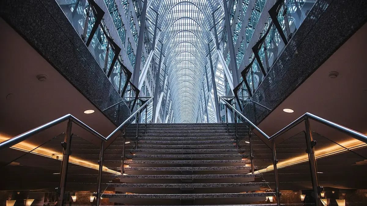 Grand escalier sous une verrière, dans le hall d’un immeuble de bureaux