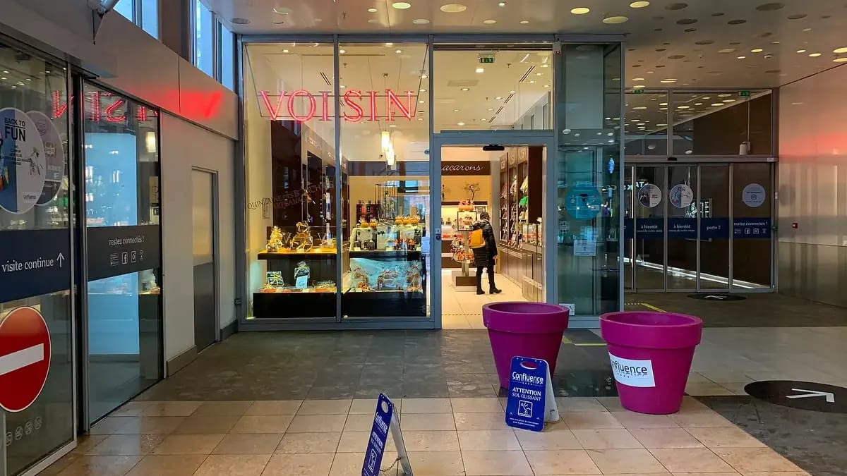 Boutique vitrée dans une galerie commerçante, vue depuis l’allée