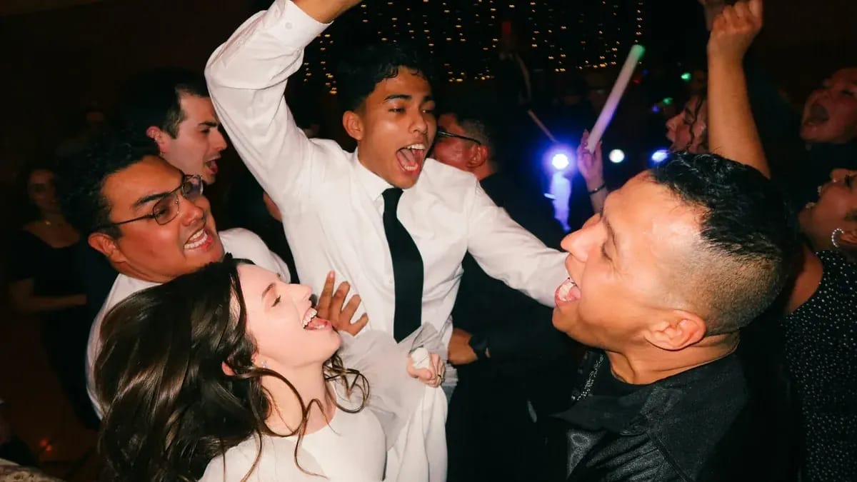Piste de danse d’un mariage : la mariée et les invités chantent, bras levés
