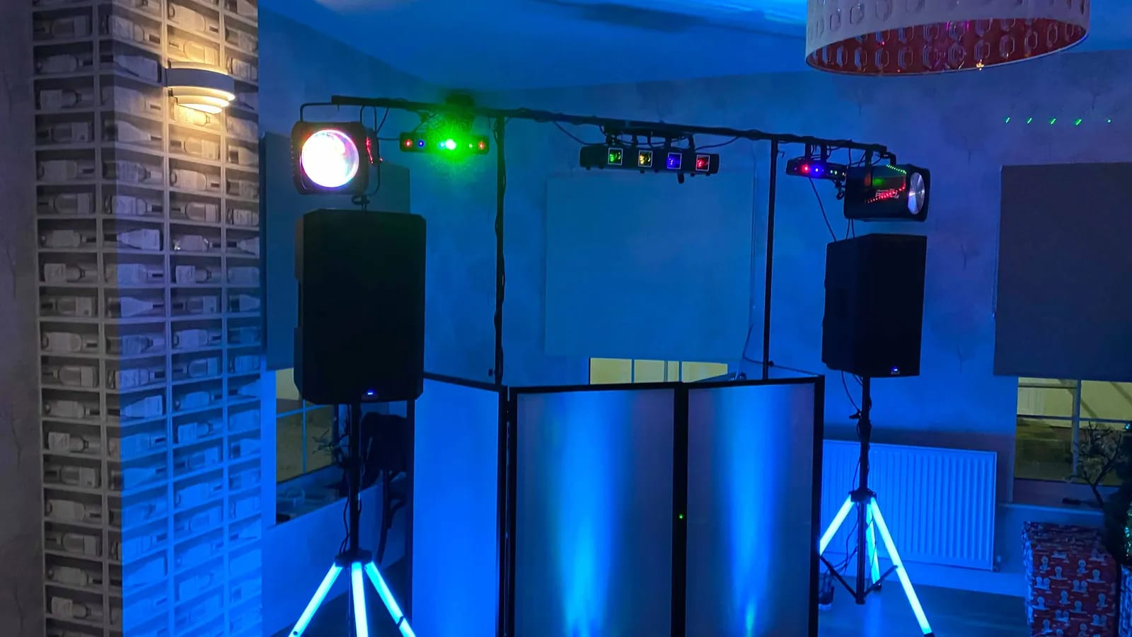 Régie DJ installée : contrôleur sur une table, barres de lumière et éclairage bleu