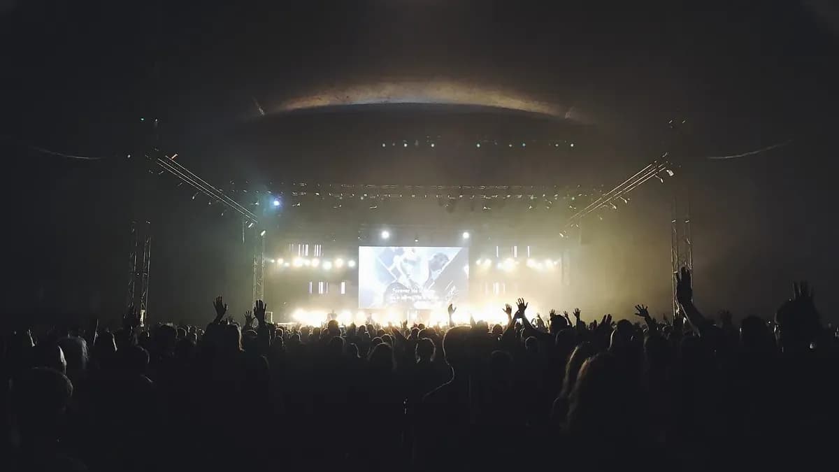 Il pubblico davanti a un palco illuminato, in una grande sala buia