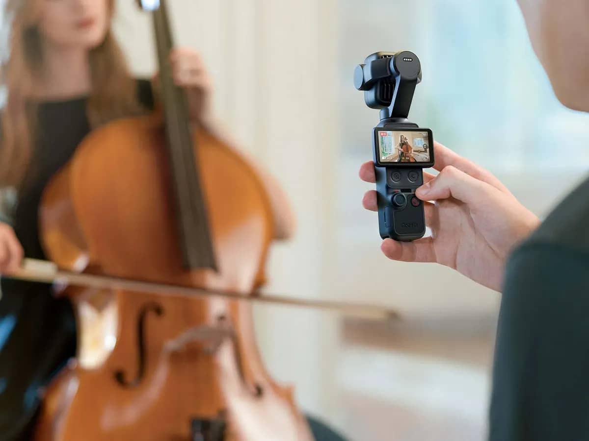 Une main tient l’Osmo Pocket 4P et filme une violoncelliste qui joue, écran allumé sur la prise de vue