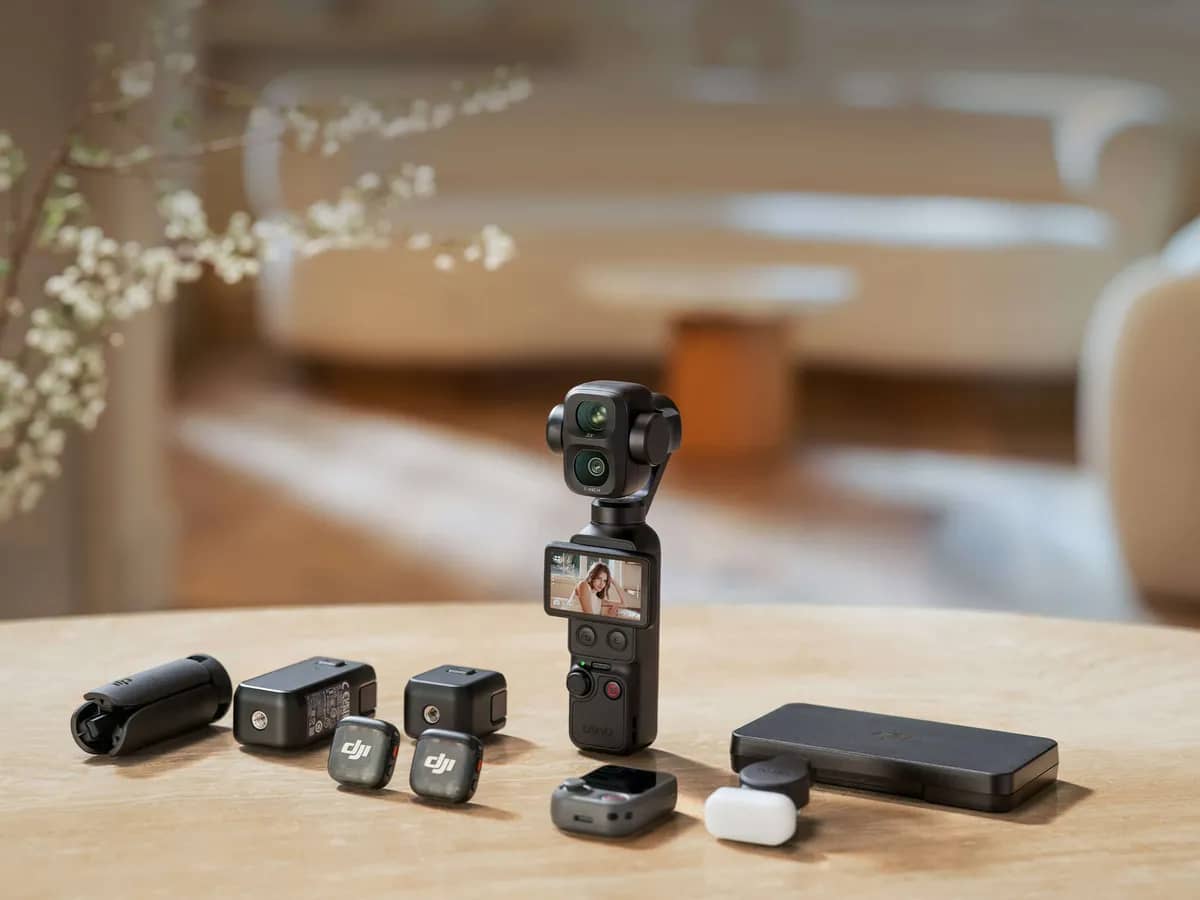 L’Osmo Pocket 4P debout sur une table, entourée de ses petits accessoires, dont deux micros sans fil