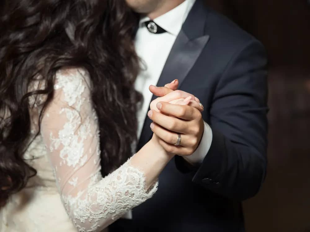Couple de mariés dansant main dans la main, vu de près sans les visages
