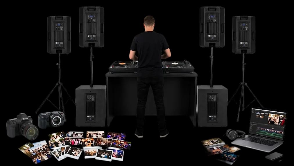 DJ aux platines entre quatre enceintes RCF ART 912-A et deux caissons RCF SUB 15-AX, appareils photo, tirages photo et Polaroid, ordinateur de montage vidéo