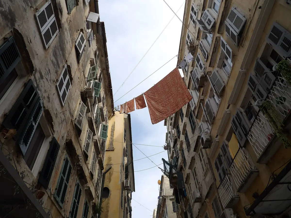 Fils à linge tendus entre deux immeubles anciens, vus depuis la rue en contre-plongée