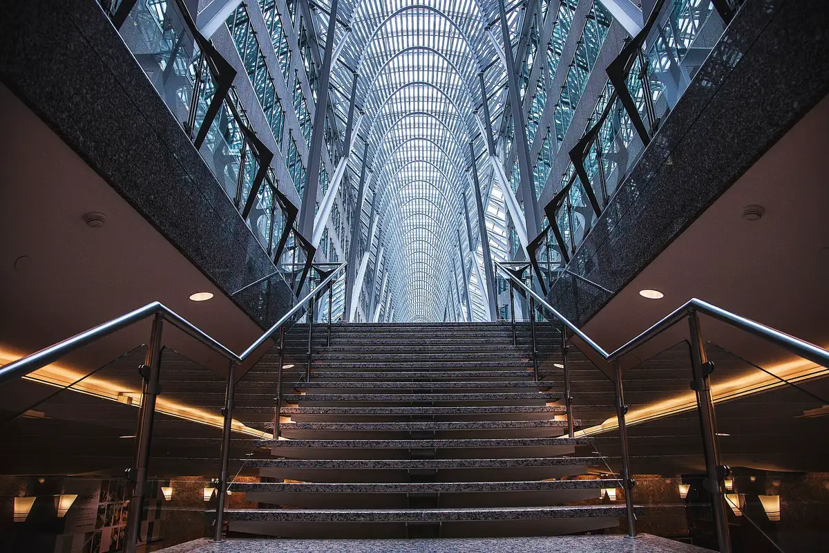 Grand volume vitré traversé par un escalier, vu depuis le bas des marches