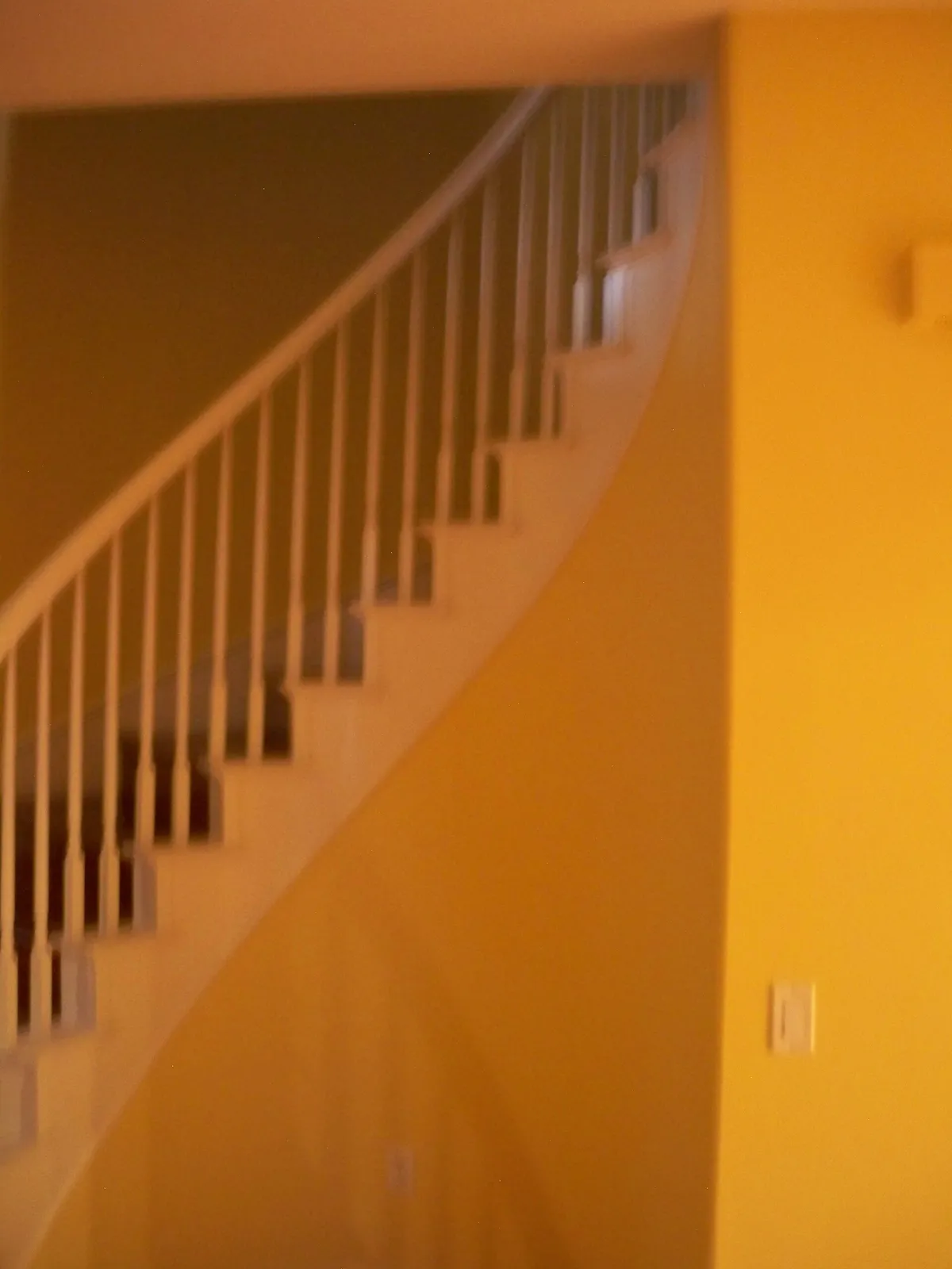Escalier tournant à limon clair contre un mur orange, sans rien autour