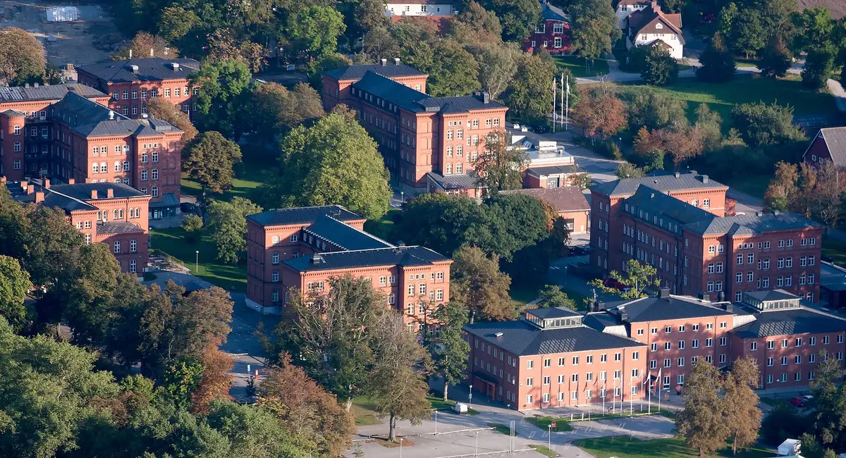 Bakstenen gebouwen op een bedrijvenpark vanuit de lucht, omringd door bomen en gazons