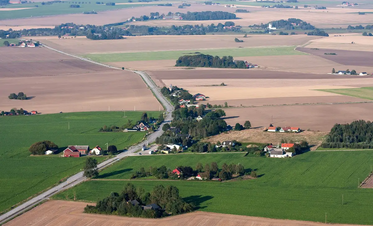 Platteland vanuit de lucht: een rechte weg, alleenstaande boerderijen en een dambord van akkers