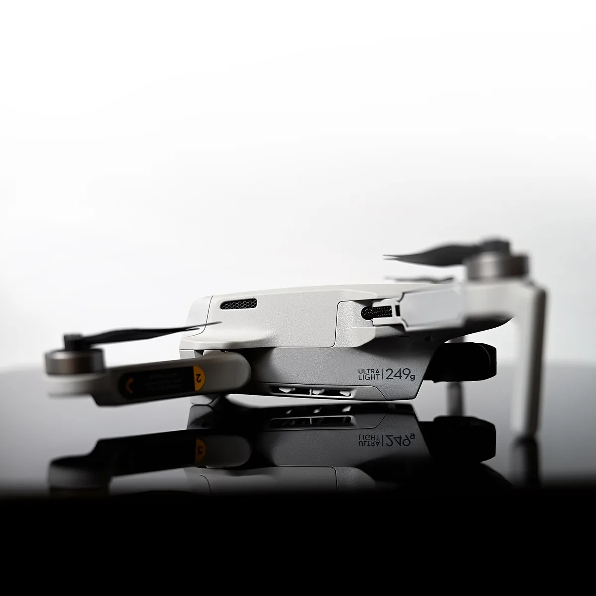 Gefaltete DJI Mini-Drohne auf einer reflektierenden Oberfläche, dunkler Hintergrund