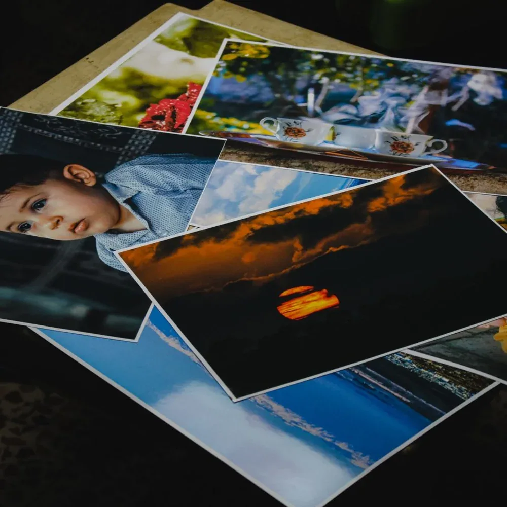 Tirages photo grand format éparpillés en désordre, portraits et paysages mêlés