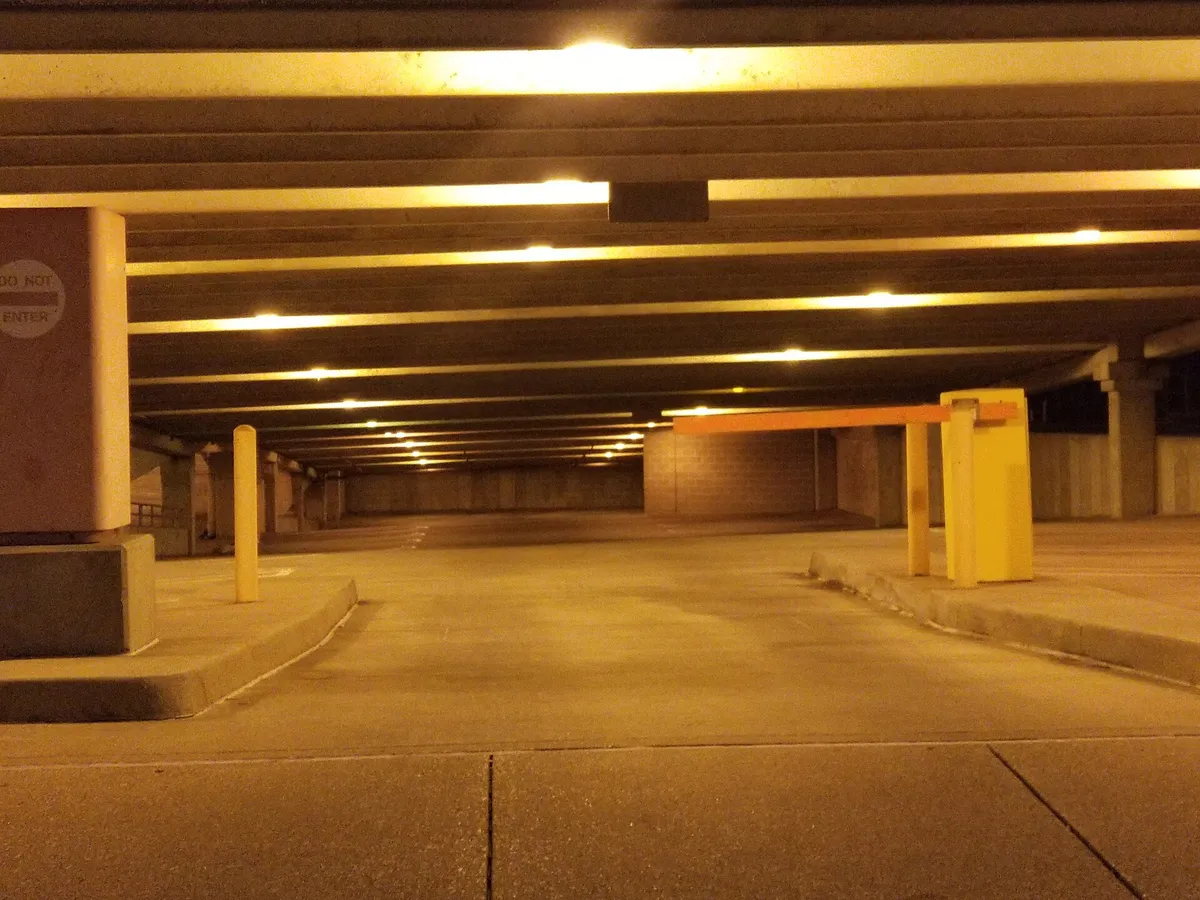 The entrance to a yellow-lit underground car park, its lifting barrier lowered