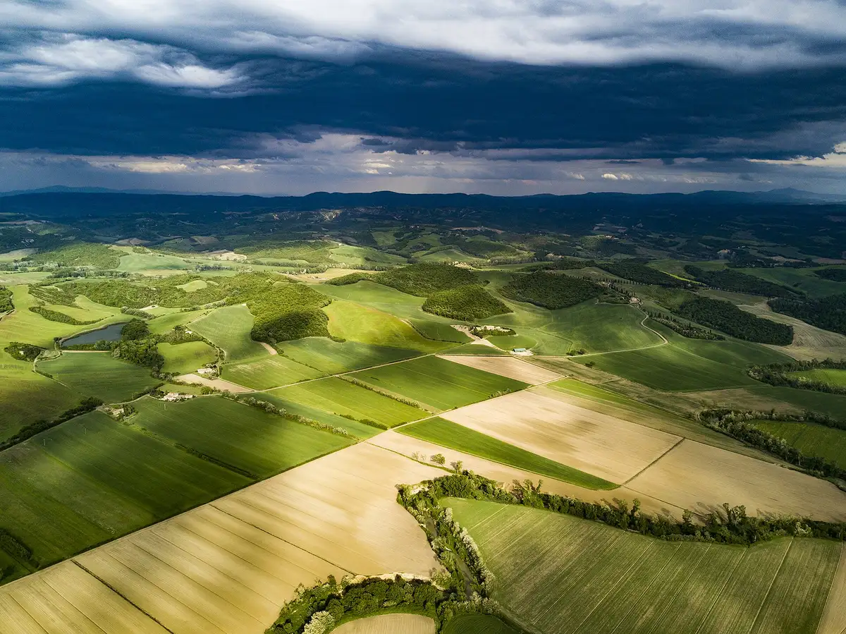 Bebouwde heuvels vanuit de lucht bij lage zon, elke plooi van het land benadrukt door zijn schaduw
