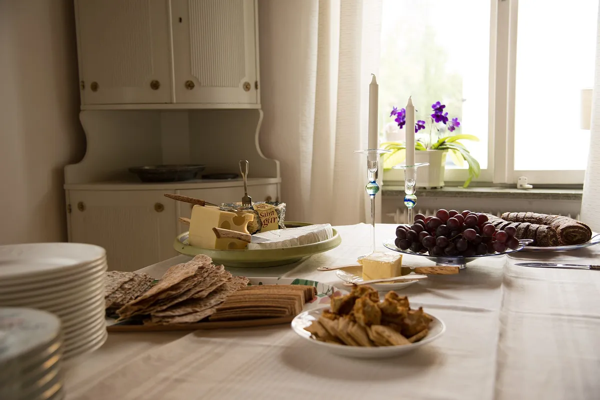Table dressée avant l’arrivée des invités : plateau de fromages, pain, bougies