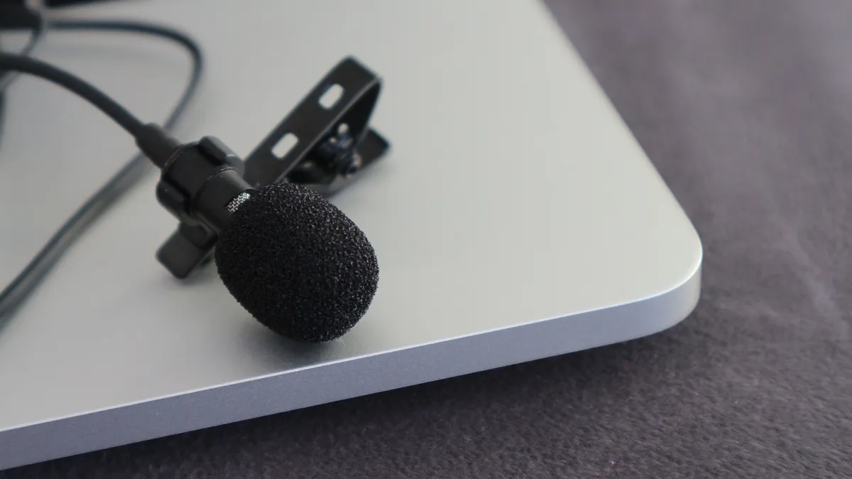 Micro-cravate noir avec sa bonnette mousse et sa pince, posé au bord d’un ordinateur portable