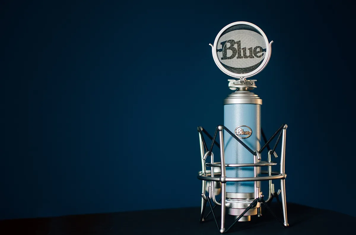 Micro de studio à large membrane, bleu clair, monté dans sa suspension araignée sur fond bleu nuit